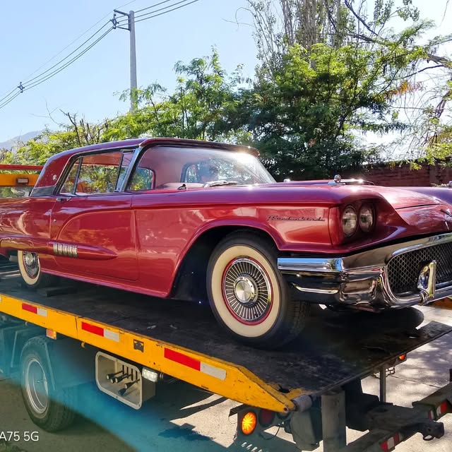 Automóvil clásico rojo sobre la plataforma de una grúa
