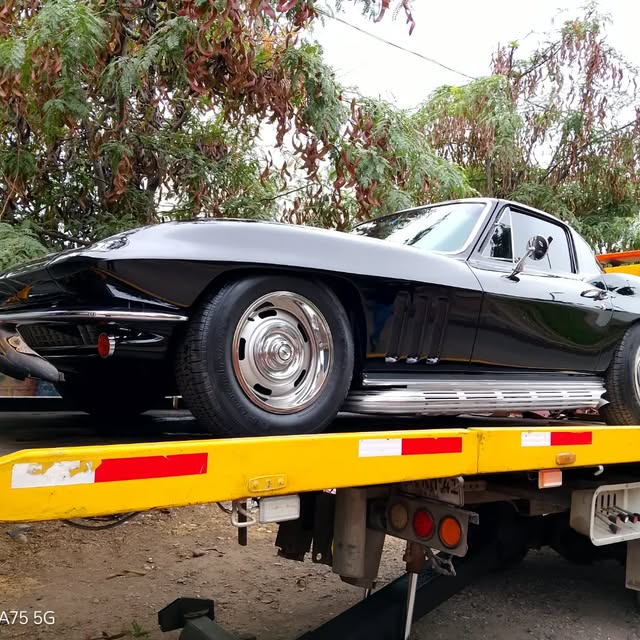Corvette clásico blanco y negro sobre una plataforma de traslado
